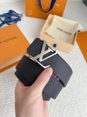 Hand holding a Louis Vuitton men's palm print belt with a stainless steel buckle, set against a backdrop of branded packaging, emphasizing luxury and quality.