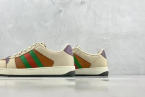 Gucci Screener distressed leather sneakers featuring beige upper, green and red stripes, and purple accents, displayed on a minimalist background.