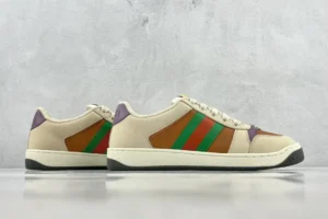 Gucci Screener distressed leather sneakers featuring a beige base with green and orange stripes and purple accents, displayed on a neutral background.
