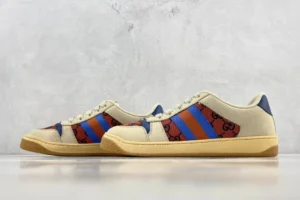Gucci Screener Distressed Leather sneakers featuring a beige canvas upper with red and blue stripes and signature logo accents, displayed on a neutral background.