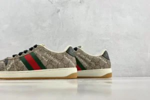Gucci Screener Distressed Leather sneakers featuring iconic GG pattern, red and green stripes, and beige color, displayed on a minimalist background.