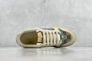 Gucci Screener Distressed Leather sneaker featuring a beige upper with blue accents and signature logo patterns, displayed from a top-down view on a neutral background.