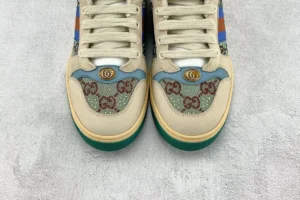 Gucci Screener Distressed Leather sneakers featuring intricate logo embroidery and colorful accents, displayed on a textured surface.