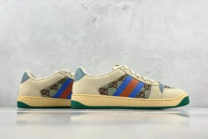 Gucci Screener Distressed Leather sneakers featuring a beige upper with blue and red stripes, showcasing the iconic Gucci logo, set against a minimalist gray background.