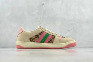 Gucci Screener Distressed Leather sneakers featuring a beige canvas, pink and green stripes, and a pink rubber sole, displayed against a textured gray background.
