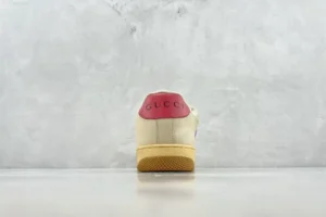 Gucci Screener Series GG Enamel used sneakers with a dirty appearance, featuring a red heel and beige body, displayed against a neutral background.