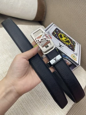 Hand holding a black Louis Vuitton belt with a 24K pure steel buckle, displayed alongside branded packaging, emphasizing luxury and quality craftsmanship.