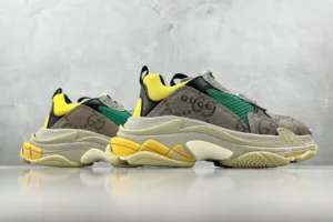 Gucci x Balenciaga Triple S sneakers in gray, yellow, and green, showcasing luxury design and branding details, featured on a textured gray background.