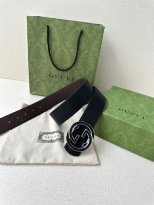 Gucci belt displayed with interlocking double G buckle, accompanied by branded packaging and dust bag, emphasizing luxury craftsmanship and versatility.