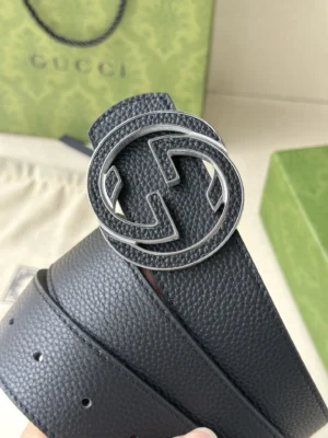 Gucci belt featuring interlocking double G buckle, crafted from black cowhide, showcasing luxury craftsmanship against a branded background.