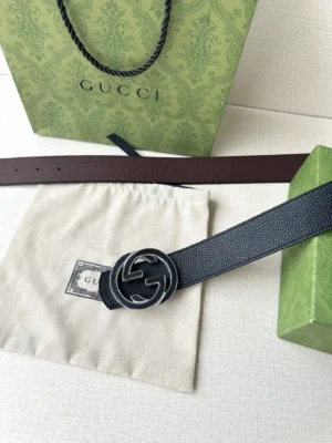 Gucci belt featuring interlocking double G buckle, displayed with a branded dust bag and green box, emphasizing luxury craftsmanship and style options.