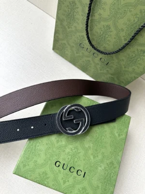 Gucci belt featuring interlocking double G buckle, displayed on green Gucci packaging, showcasing grey and black cowhide craftsmanship.