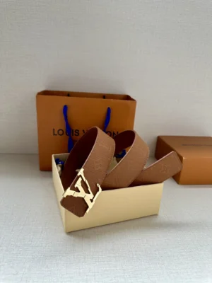 4.0-wide LV Shadow belt with Monogram displayed in a box, featuring a gold LV buckle, alongside Louis Vuitton shopping bag and packaging, emphasizing luxury fashion accessory.