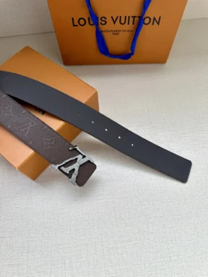 4.0-wide LV Shadow belt with Monogram displayed on a surface beside an orange Louis Vuitton shopping bag, featuring a sleek black leather strap and a distinctive LV buckle.