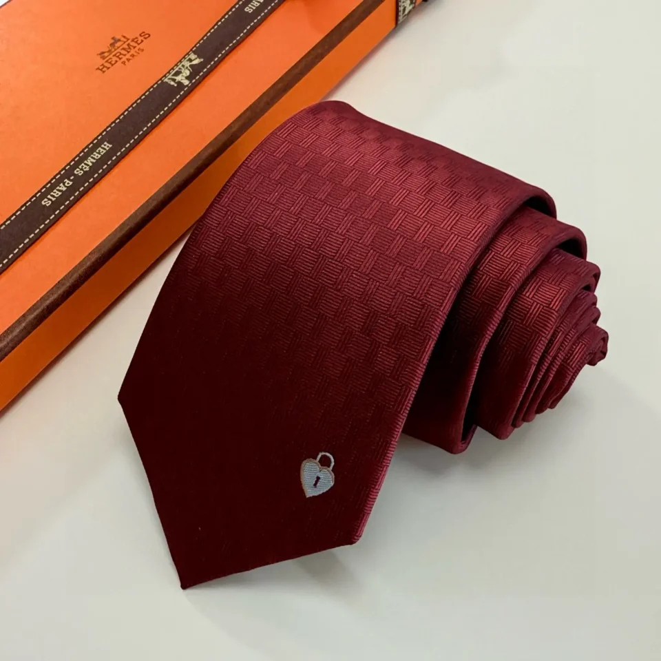 Hermès tie burgundy silk with subtle basketweave pattern and silver heart lock embroidery detail