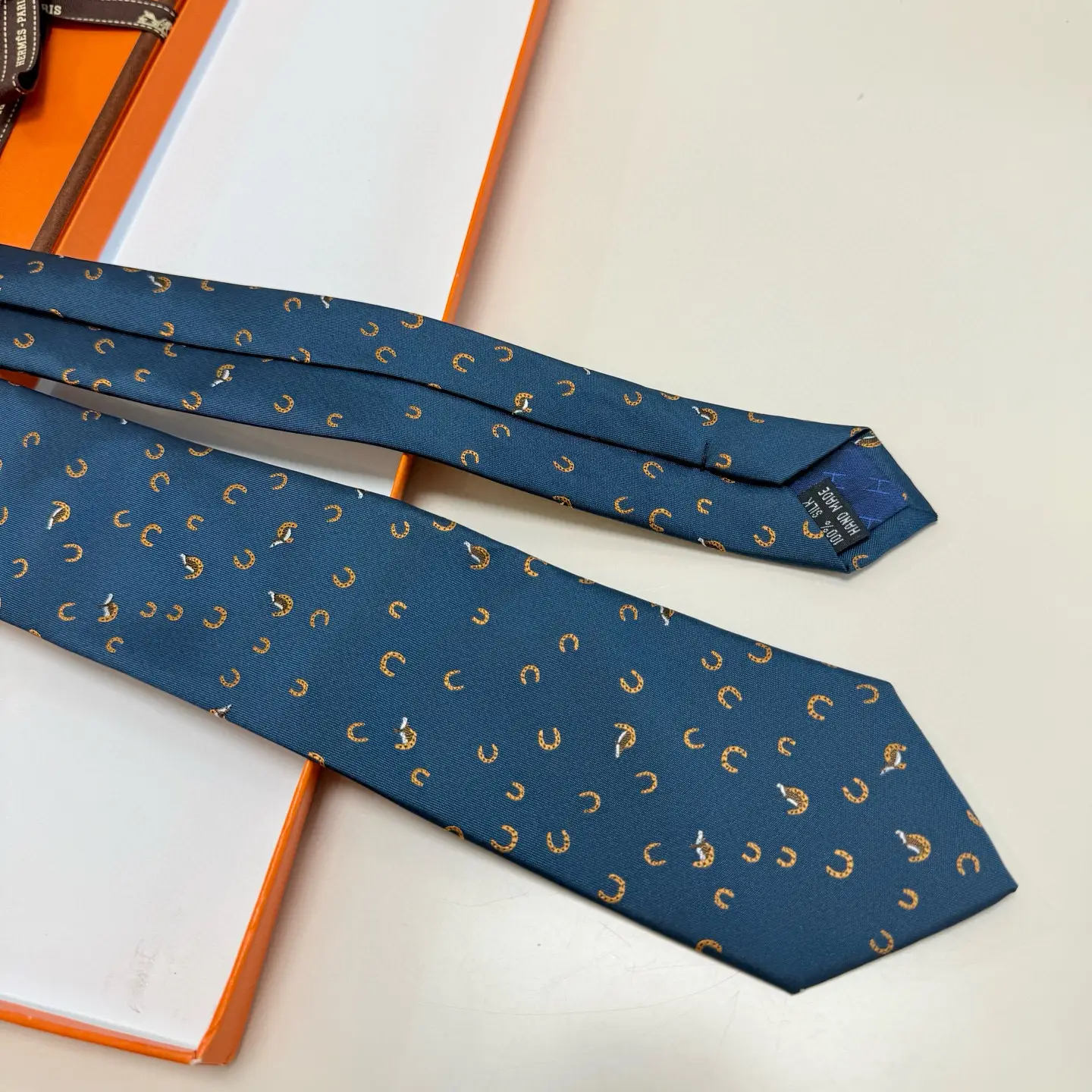 Hermès tie blue silk featuring small orange horseshoe and animal motifs luxury accessory