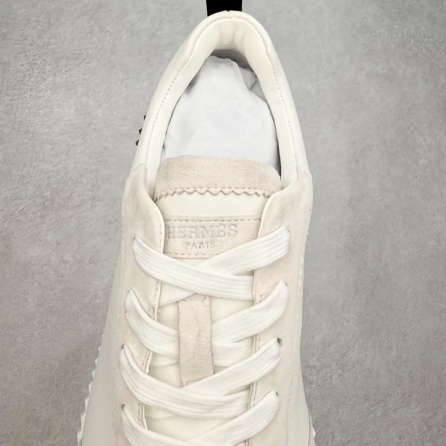 Hermes Men’s Bouncing Sneaker in Technical Mesh, featuring a light-colored upper, lace closure, and embossed logo, emphasizing luxury footwear design.