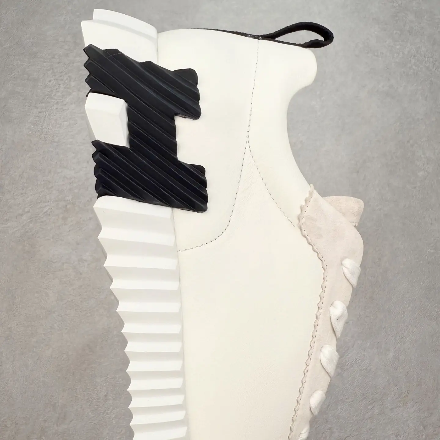 Hermes Men’s Bouncing Sneaker featuring a white technical mesh upper, distinctive black textured heel, and detailed outsole design, emphasizing luxury craftsmanship and style.