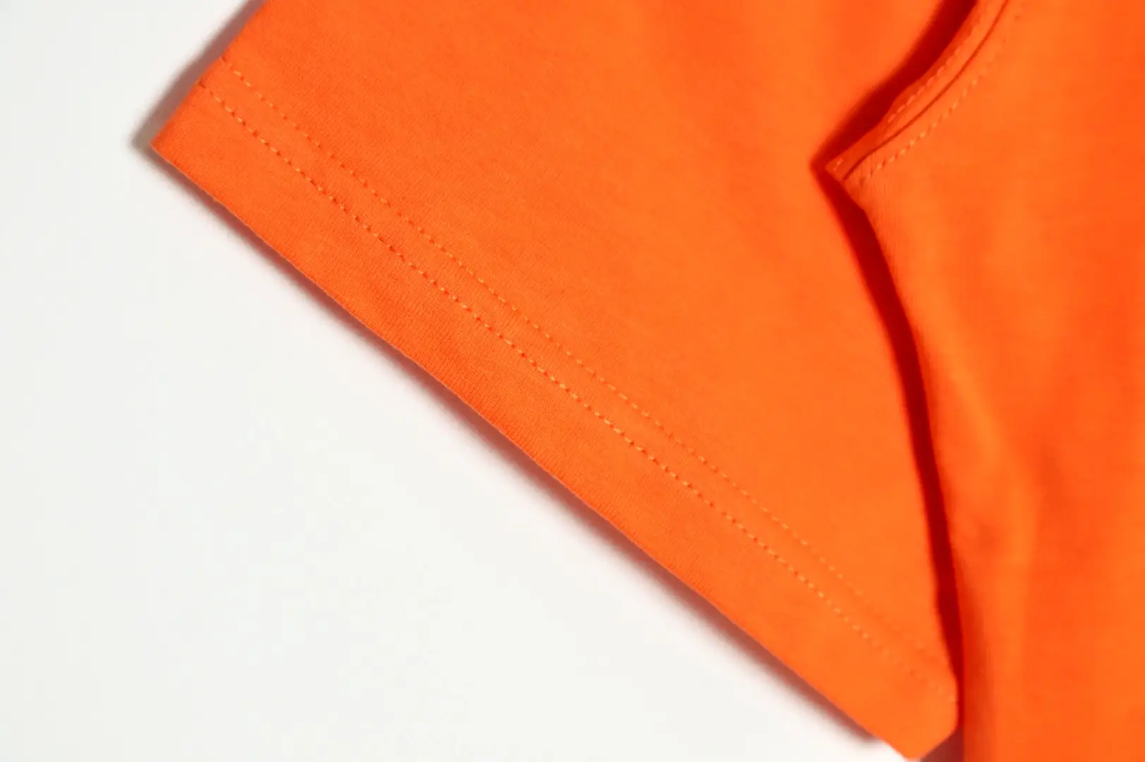 RepsGoat orange cotton T-shirt close-up of stitched hem on white background