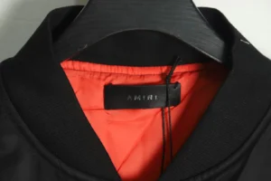 Amiri bomber jacket black nylon shell orange satin lining collar close-up