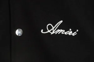 Amiri logo embroidered on a black varsity bomber jacket, showcasing premium craftsmanship and design details.