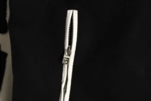 Close-up of the zipper detail on the Amiri Wool Blend Bones Appliquéd Varsity Bomber Jacket, showcasing the contrasting white zipper against the black fabric.