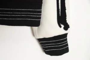 Amiri Wool Blend Bones Appliquéd Varsity Bomber Jacket sleeve detail showcasing black and white fabric, ribbed cuffs, and contrasting stripes.