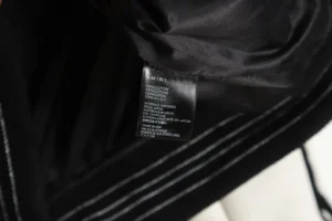 Amiri Wool Blend Bones Appliquéd Varsity Bomber Jacket interior showing copper ammonia silk lining and care label details.