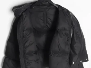 No brand or model visible, black puffer jacket with zipper and snap button details made of nylon material