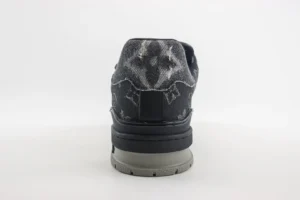 Louis Vuitton Trainer low-cut sneaker showcasing black and gray patterned upper, distinct logo design, and rubber outsole, emphasizing luxury replica footwear.