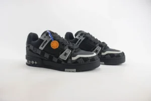 Louis Vuitton Trainer low-cut sneakers in black with contrasting white accents, featuring unique strap detailing and an orange tag, highlighting luxury design and craftsmanship.