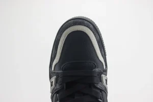 Close-up view of the toe of a Louis Vuitton Trainer sneaker, featuring a black leather design with gray accents and a textured finish, highlighting luxury footwear details.