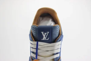Tyler x Louis Vuitton Trainer sneaker featuring blue and brown colorway, prominent LV logo on the tongue, and intricate lacing design, showcasing luxury craftsmanship.