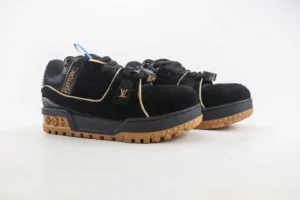 Louis Vuitton Trainer sneakers in black suede with gold accents and a gum sole, showcasing luxury craftsmanship and style.