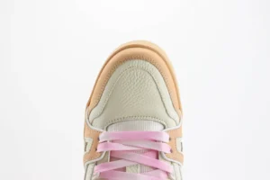 Close-up of a Louis Vuitton Trainer low-cut casual sneaker showcasing a cream and peach color scheme with pink laces, highlighting the shoe's premium materials and craftsmanship.