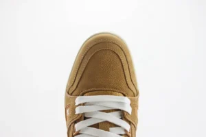 Close-up of the toe area of a Louis Vuitton Trainer low-cut casual sneaker in tan color with white laces, showcasing the texture and design details.