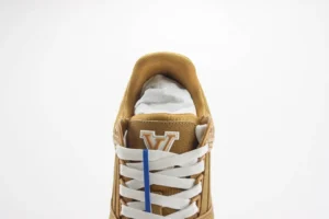 Louis Vuitton Trainer low-cut casual shoe featuring a tan upper, white laces, and logo detail on the tongue, showcasing luxury replica footwear design.