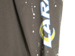 GALLERY DEPT GD Inkjet Hot Stamped Letter Hoodie sleeve featuring bold blue lettering and splatter design on a dark fabric background.