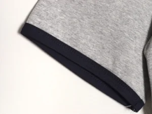 I see the image shows a close-up of a garment sleeve edge with grey fabric and navy blue trim, but no brand or model information is visible. Please provide the product details or another image with the product name, brand, or specific type for accurate alt text according to your SEO rules.