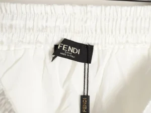 Fendi label on white jacquard beach shorts, highlighting luxury designer craftsmanship and brand authenticity.