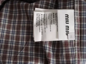 MIU MIU brown and blue fine grid long sleeve shirt fabric with care label and brand tag, showcasing quality craftsmanship and luxury fashion details.