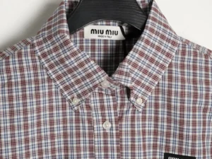 MIU MIU Brown Blue Fine Grid Long Sleeve Shirt featuring a checkered pattern, collar, and brand label, emphasizing luxury fashion design and craftsmanship.