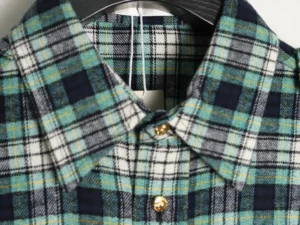 Celine green plaid flannel shirt collar with gold buttons and tag, showcasing casual style and craftsmanship.