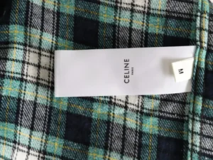 Celine label on green plaid flannel shirt, featuring a checked pattern with blue and yellow accents, showcasing premium fabric quality.