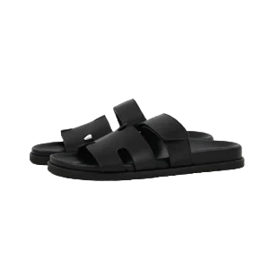 Black Hermes Chypre flat slippers with open toe design and dual straps, showcasing luxury footwear style for casual wear.
