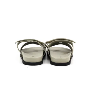 Hermes flat one-word slippers in beige, showcasing the back view with a minimalist design and flat sole, emphasizing luxury footwear features.