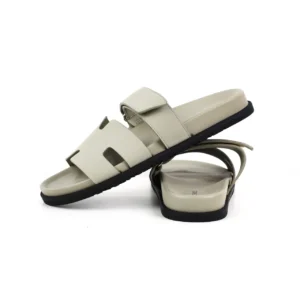 Hermes flat one-word slippers in beige leather with a flat sole, showcasing a modern and minimalist design, ideal for luxury footwear enthusiasts.