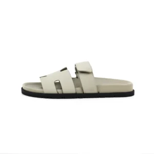 Hermes flat one-word slippers in light color with two straps and a flat sole, showcasing luxury footwear design for casual wear.