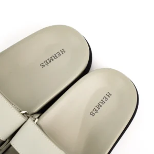 Hermes flat slippers with embossed logo, featuring a minimalist design and neutral color, showcasing luxury footwear for casual wear.