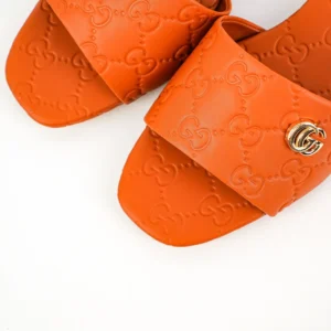 Gucci Double G women's slippers in orange sheepskin leather with embossed logo and gold double-G accessory.
